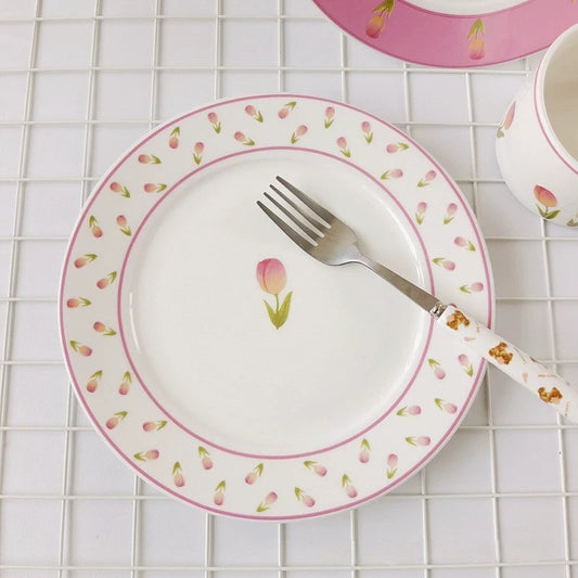 white ceramic plate with a floral pattern, featuring a central tulip design, surrounded by a pink border with more floral accents