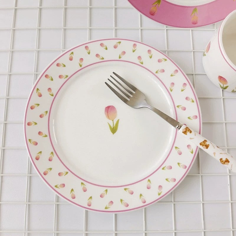  white ceramic plate with a floral pattern, featuring a central tulip design, surrounded by a pink border with more floral accents